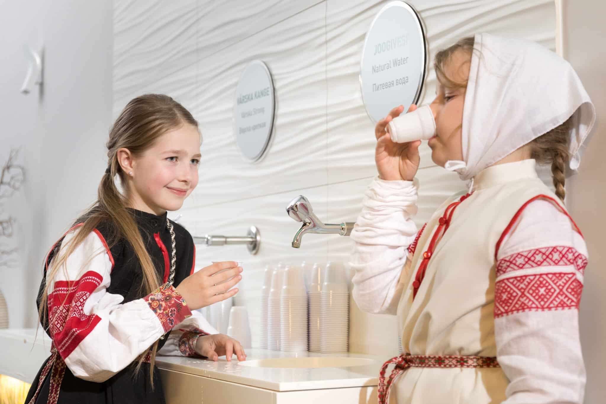Girls dressed in Seto costumes tasting natural mineral water straight from the tap at the Värska Health Resort Centre.