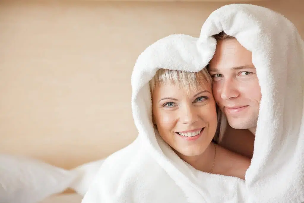 Молодые мужчина и женщина в халатах в номере санатория на кровати в лечебном центре курорта Вярска.
