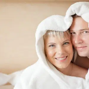 A young man and woman in bathrobes in a sanatorium hotel room on a bed at the Värska spa treatment centre.