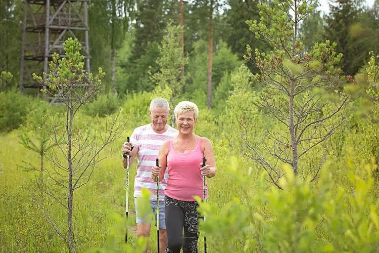 Sieviete un vīrietis ar spieķa nūjām pastaigājas laukos netālu no Värska spa ārstniecības centra.