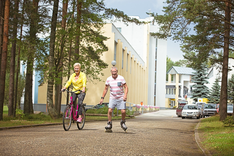 A woman rides a bicycle and a man rollerblades on a cycle path near the Värska spa treatment centre.