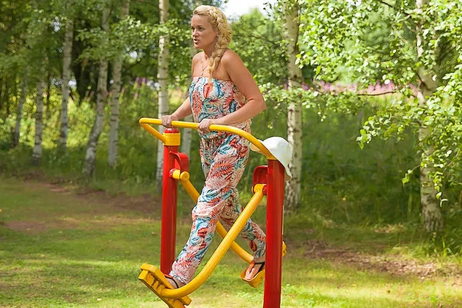 A woman trying out an outdoor gym on the beach area health area.