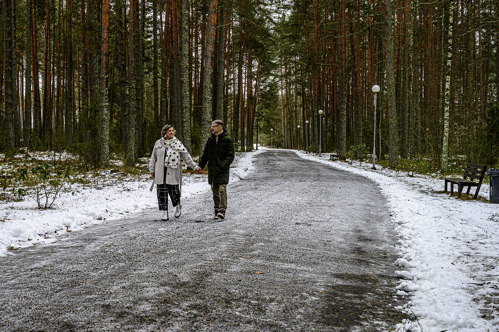 Armunud keskealine paar jalutab lumisel teel männimetsas Värska sanatooriumi juures